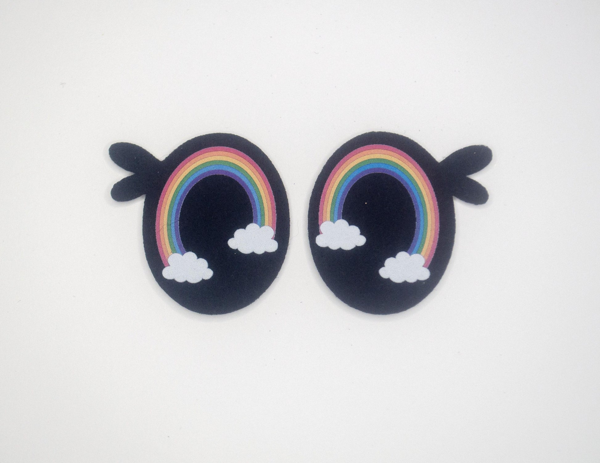 a pair of earrings with a rainbow and clouds on them