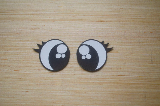 a pair of black and white earrings on a wooden surface